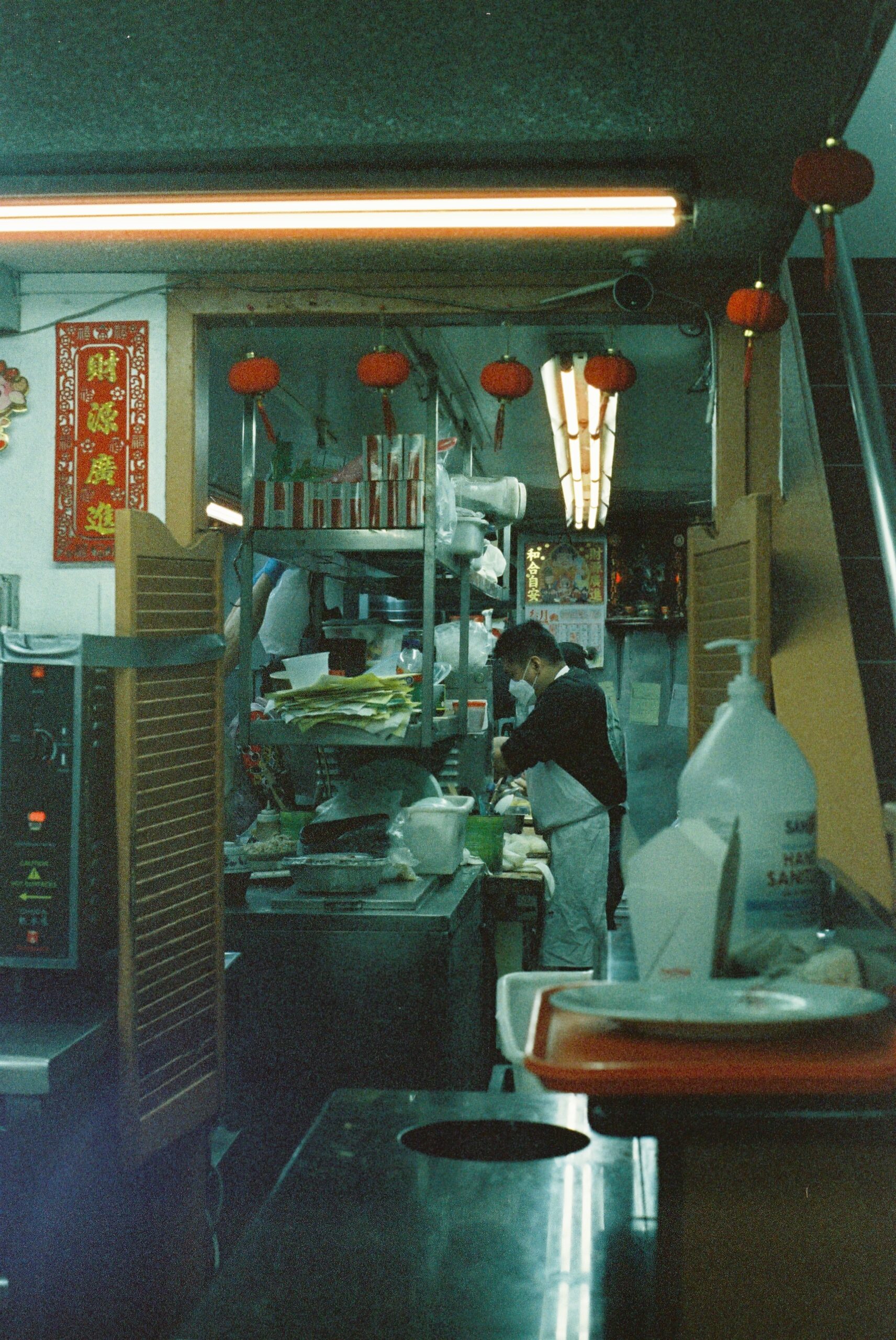 an aproned man wearing a face mask prepares a take out order at a Chinese restaurant