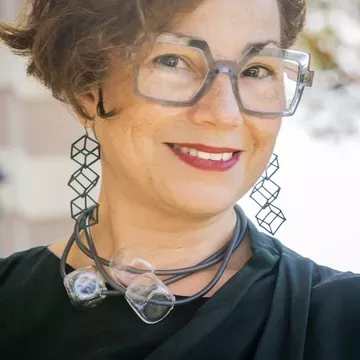 Jennifer Brody, person with curly brown hair, wearing glasses looking into the camera