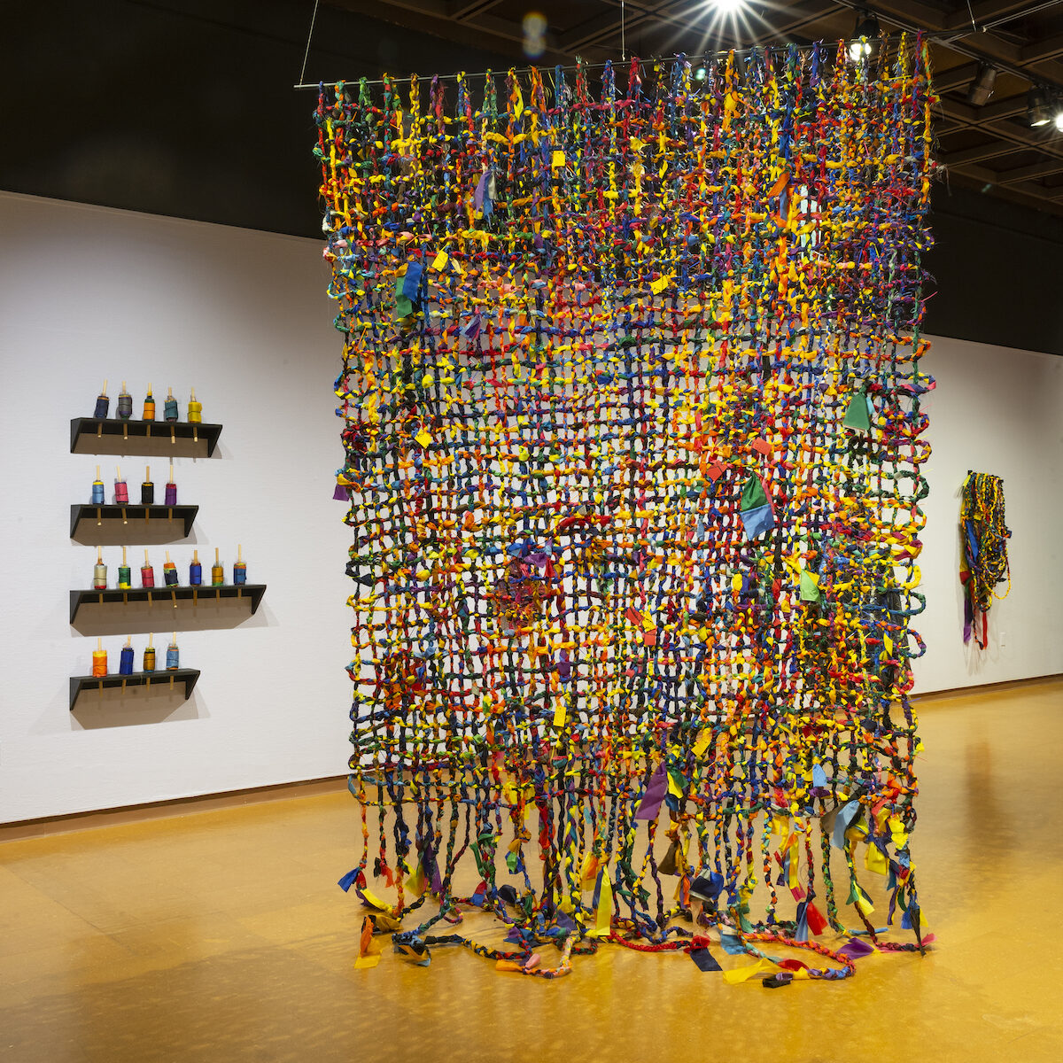 a brightly colored textile piece hangs in a gallery