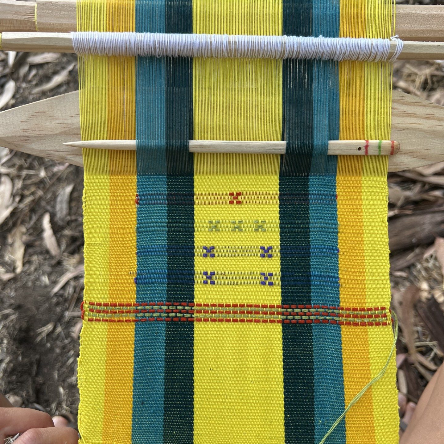 a photo of cloth being woven on a loom