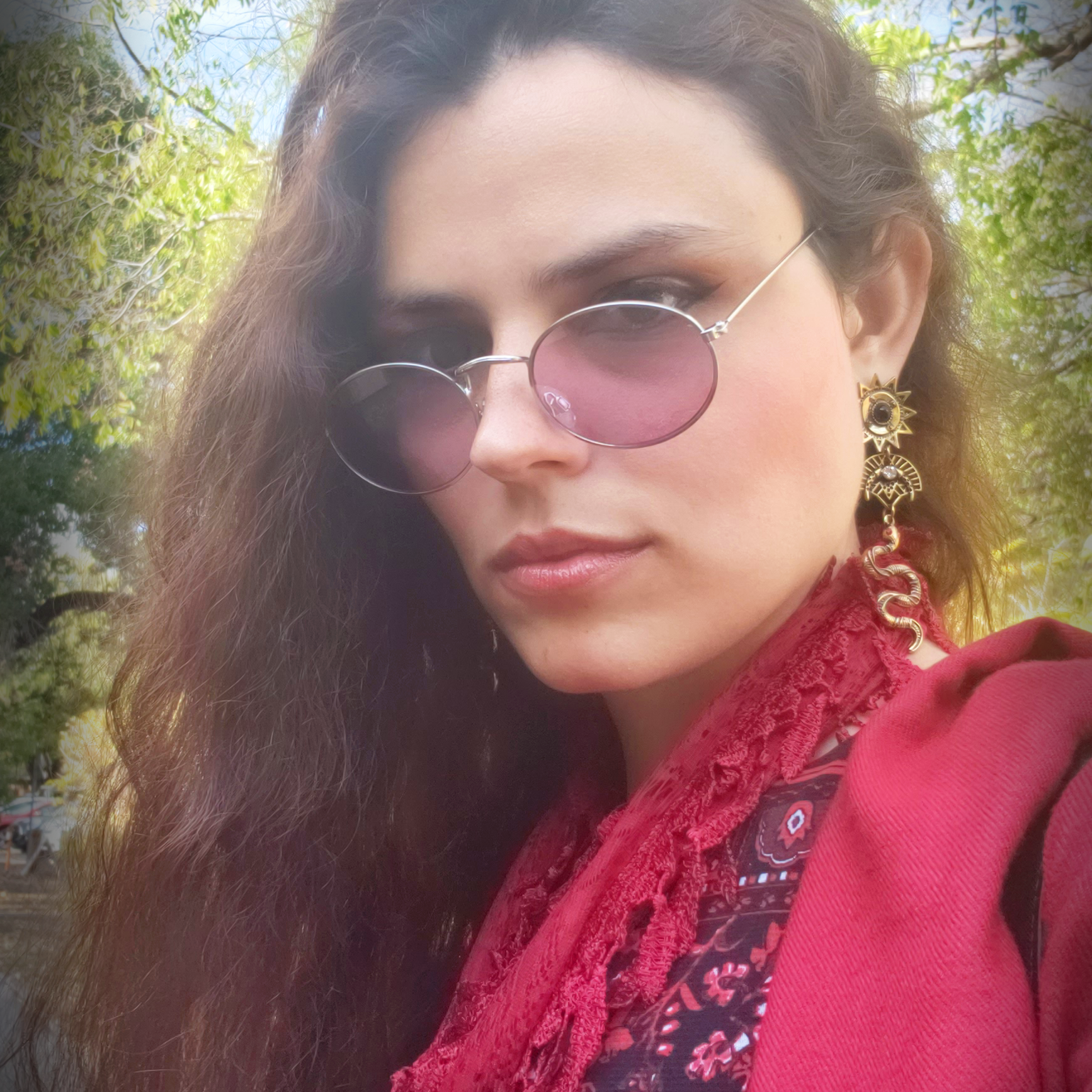 Photo of Douris, a long-haired person in a red vest and scarf
