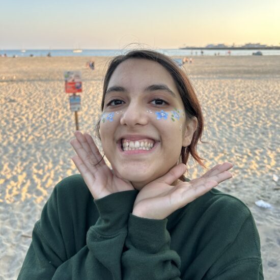 a photo of Zuni on a beach with blue glitter on her cheeks