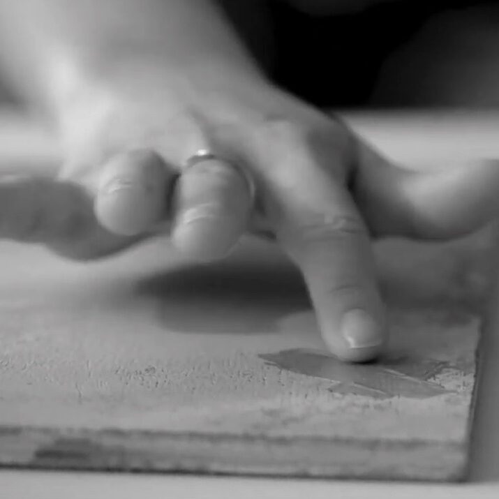 hand applying paint to wood