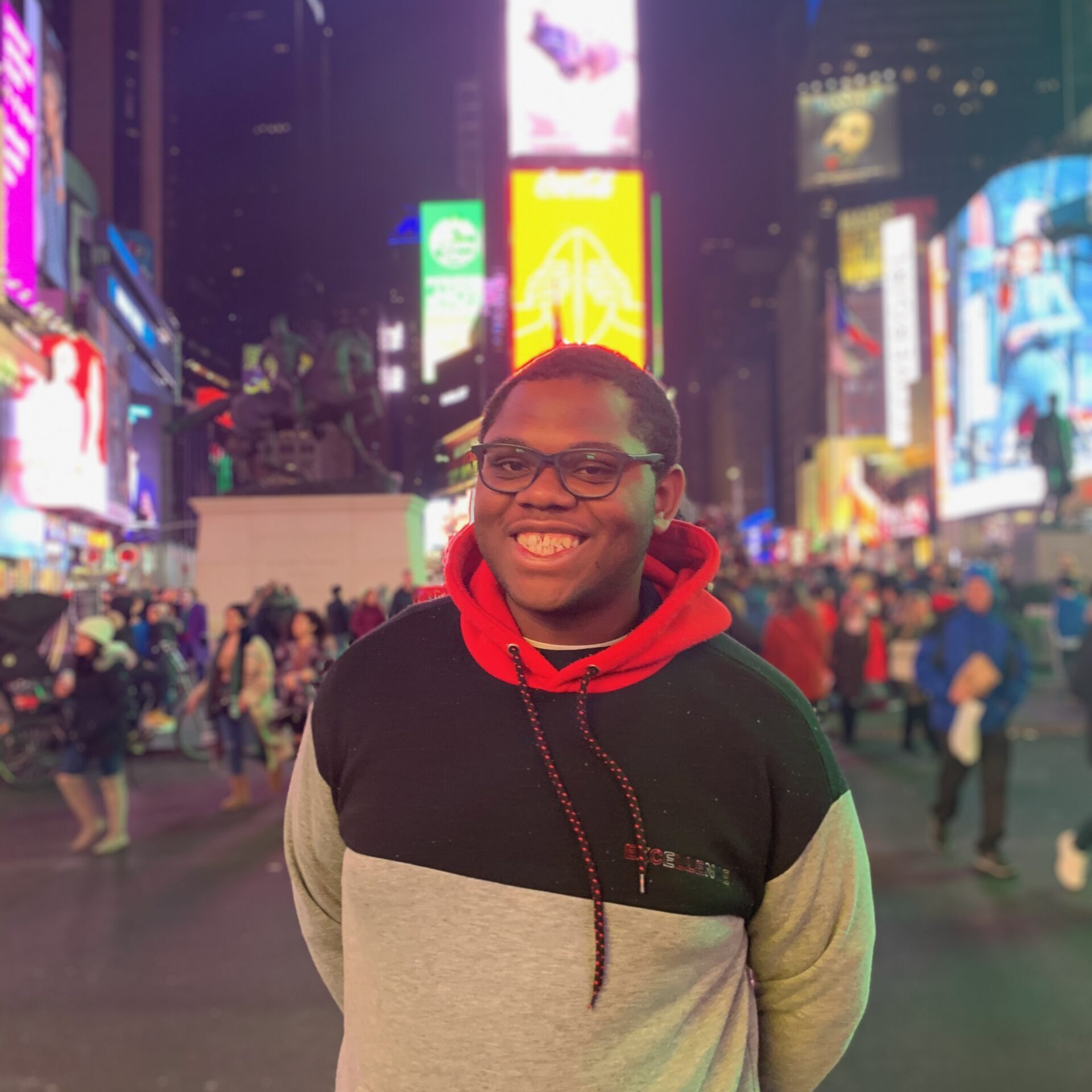 Portrait of Micheal Brown: a young black man standing in Times Square at night