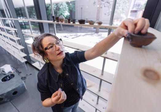 Erika Chong Shuch, Stanford Arts' 2025–26 visiting artist, attends the installation of her exhibition 1,000 Ways to Hold at the Anderson Collection at Stanford University. The show is the culmination of a year-long participatory project rooted in conversation and clay, in which pairs of participants shaped ceramic bowls while reflecting on questions of memory, care and human connection.