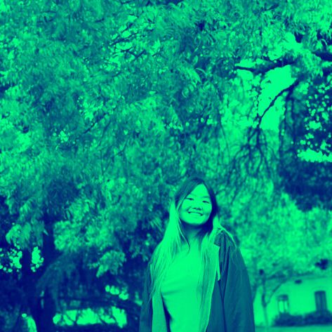 A photo of Lyda in front of a tree with a bright green monochromatic filter