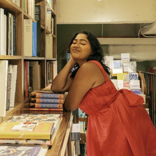 A photo of Malavika in a red dress amidst piles of books