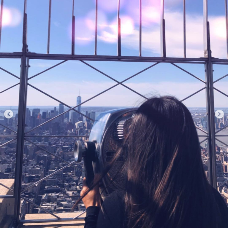 a woman stares out at New York City from an observation deck