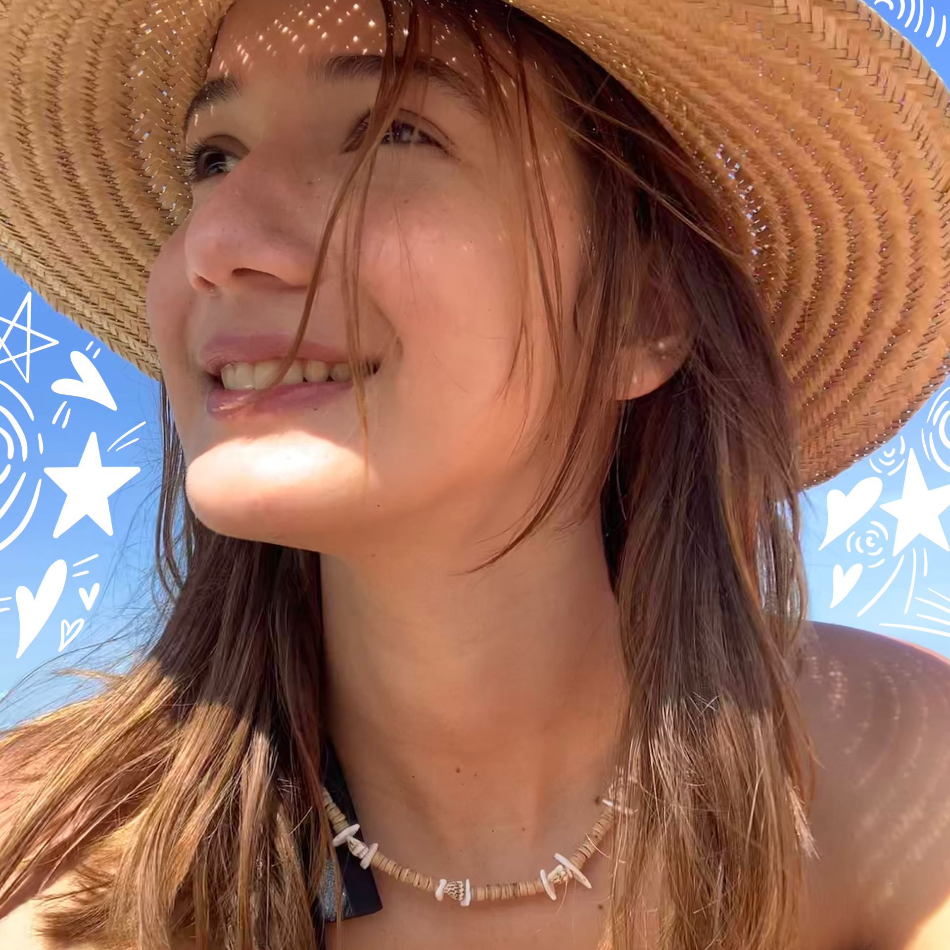 A photo of Mia in a sunhat with doodles of stars on the bright blue sky behind her