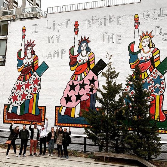 a group of student pose in front of an outdoor mural of the statue of liberty