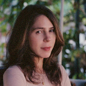 Rachel Kushner sitting at an angle in front of a background with trees