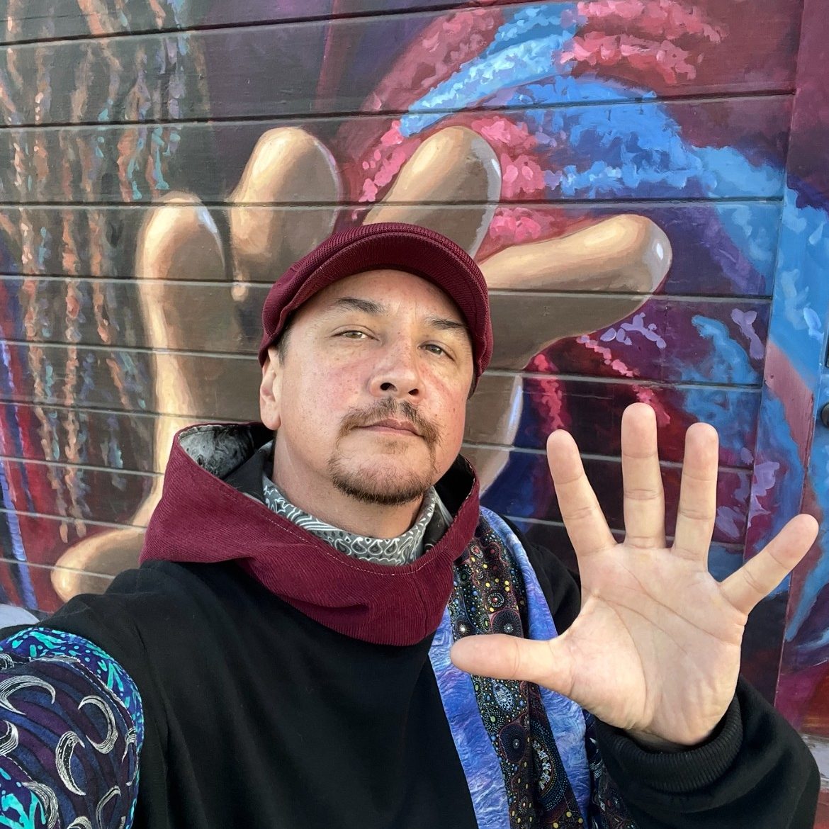 Person standing in front of a mural.