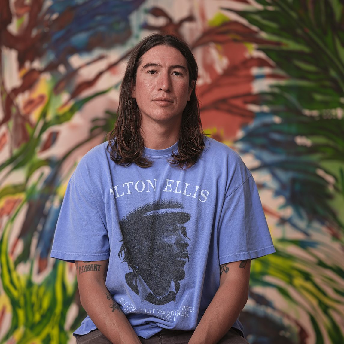 Person in blue shirt sitting in front of artwork