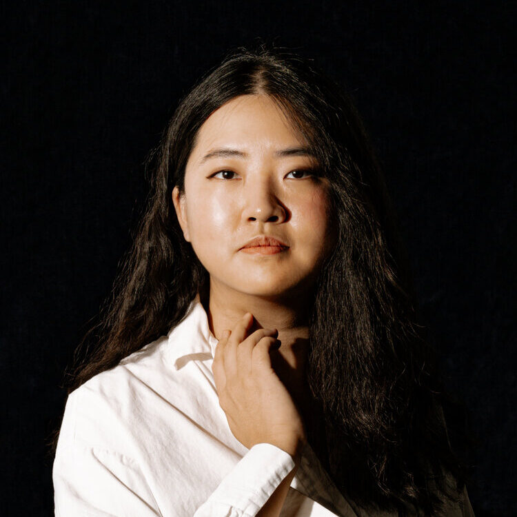 Scarlett Kim wearing a white button up in front of a black background