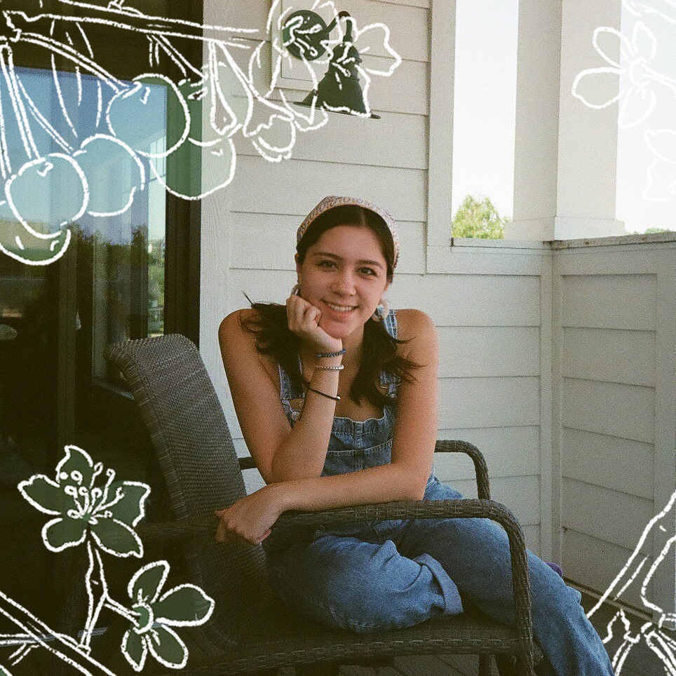 a photo of Sherry Nolan wearing jeans and a tank top on a front porch, with white pencil sketches of flowers and berries