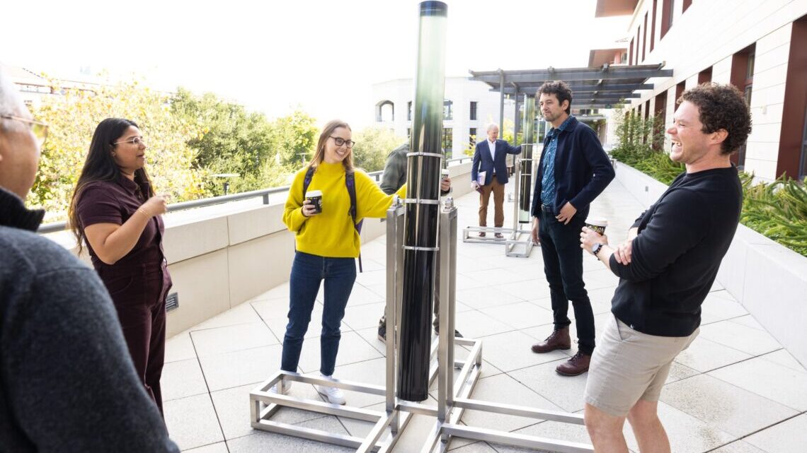 Viewers spin acrylic columns filled with seawater and iron filings at the unveiling of Sea of Dust. The installation will be on display at the Yang and Yamazaki Environment and Energy Building through the 2024 academic year. (Image credit: Steve Fisch)