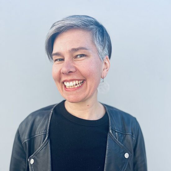 a person with short hair smiling at the camera