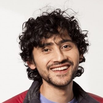 A photo of Manu Prakash in a red jacket against a white background