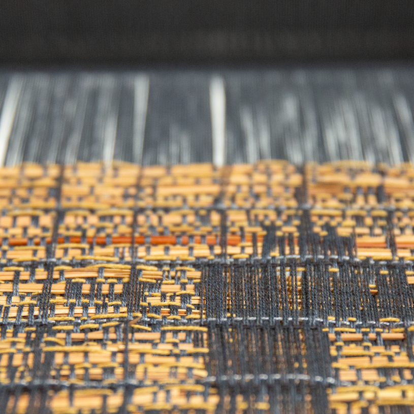a close-up photo of a black and tan textile on the TC2 loom