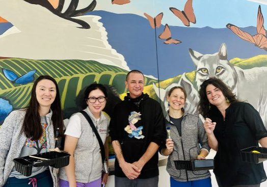 Staffers Jeanie Liang, Hyun Lee, Amy Huffaker, and Antonia Dapena-Tretter helped to paint a mural created by artist Ryan Martinez (center), featuring California landscapes and animals.