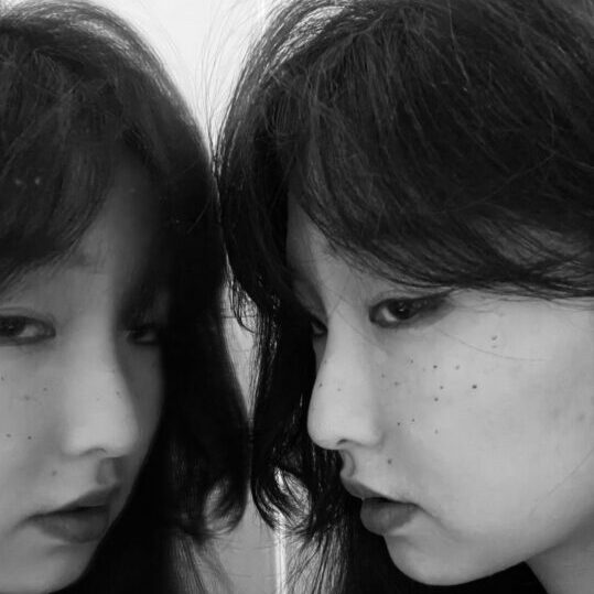 A black and white photo of Yuer and her reflection in a mirror